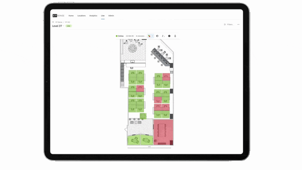 nimated dashboard displayed on a tablet showing a live office floor plan with color-coded workspaces that update in real time to visualize occupancy, desk availability, and indoor air quality across the workplace.